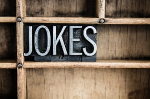 The word "JOKES" written in vintage metal letterpress type in a wooden drawer with dividers.